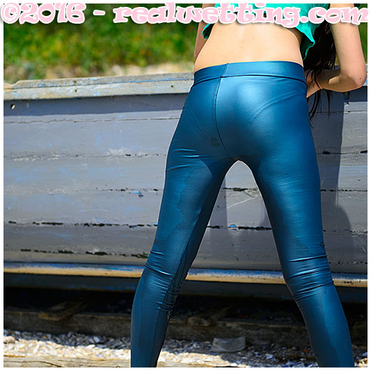 Debbie pees her blue shiny leggings on the beach wetting herself