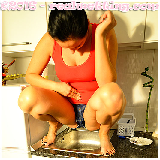 Bulging bladder pisses her jeans over the kitchen sink